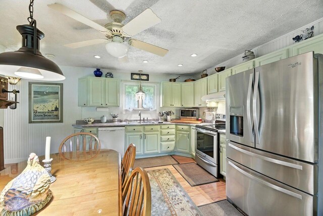8454 Stickles Rd, Three Oaks, MI 49128 - kitchen featuring appliances with stainless steel finishes, green cabinets, light wood-type flooring, hanging light fixtures, and a textured ceiling