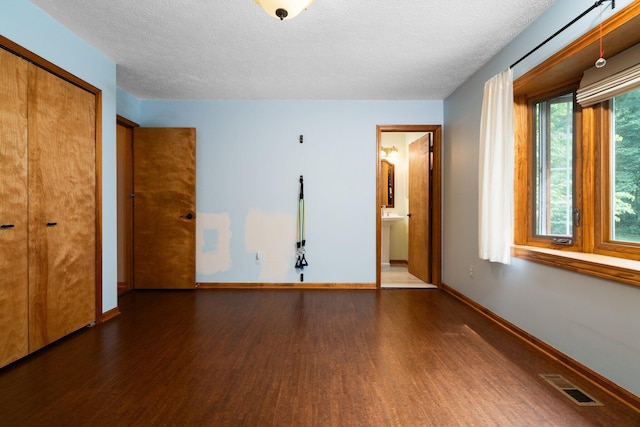 3395 Simsbury Dr, Pinckney, MI 48169 - unfurnished bedroom with wood finished floors, a textured ceiling, a closet, and ensuite bath