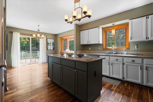 3395 Simsbury Dr, Pinckney, MI 48169 - kitchen with a chandelier, dark wood-type flooring, gray cabinets, a center island, and a textured ceiling