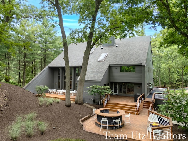410 Greentree Ln NE, Ada, MI 49301 - rear view of house featuring a fire pit, a wooden deck, and a shingled roof