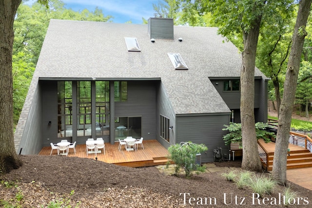 410 Greentree Ln NE, Ada, MI 49301 - rear view of property with a shingled roof, a wooden deck, and a chimney