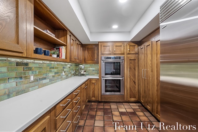 410 Greentree Ln NE, Ada, MI 49301 - kitchen with appliances with stainless steel finishes, decorative backsplash, open shelves, brown cabinetry, and light countertops