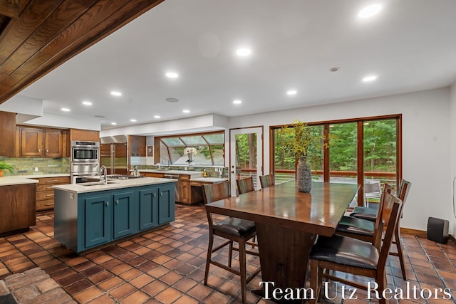 410 Greentree Ln NE, Ada, MI 49301 - kitchen featuring light countertops, decorative backsplash, recessed lighting, a kitchen island with sink, and appliances with stainless steel finishes