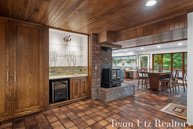 410 Greentree Ln NE, Ada, MI 49301 - kitchen featuring beverage cooler, wooden ceiling, tasteful backsplash, a wood stove, and light countertops