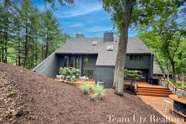 410 Greentree Ln NE, Ada, MI 49301 - back of house with a deck, a shingled roof, and a chimney