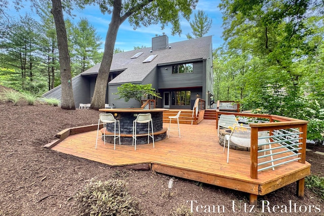 410 Greentree Ln NE, Ada, MI 49301 - rear view of house with a wooden deck, a chimney, and a shingled roof