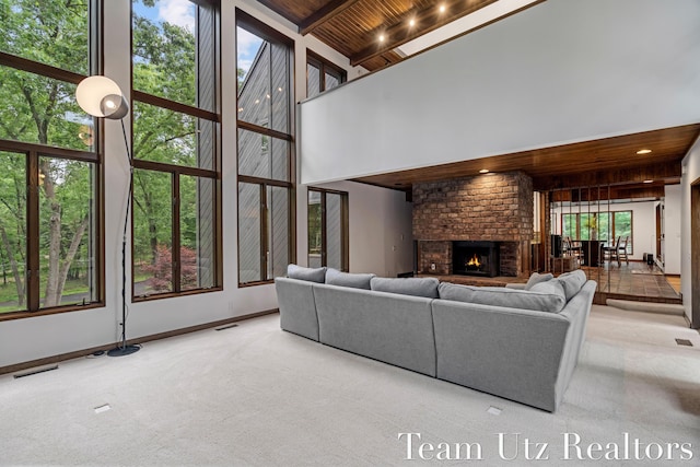 410 Greentree Ln NE, Ada, MI 49301 - carpeted living room with a wood ceiling with exposed beams, a brick fireplace, a high ceiling, and healthy amount of natural light