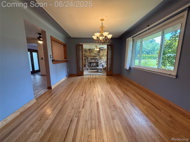 53240 Odilon Ave, Shelby Twp, MI 48316 - unfurnished dining area with light wood-style flooring, a chandelier, a fireplace, and a ceiling fan