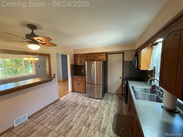 53240 Odilon Ave, Shelby Twp, MI 48316 - kitchen featuring appliances with stainless steel finishes, a ceiling fan, brown cabinetry, and a chandelier
