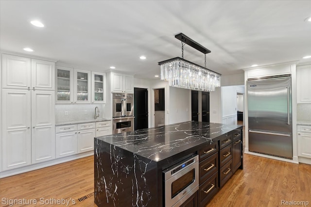 4438 Stony River Dr, Bloomfield Hills, MI 48301 - kitchen with built in appliances, white cabinetry, light wood-style flooring, glass insert cabinets, and recessed lighting