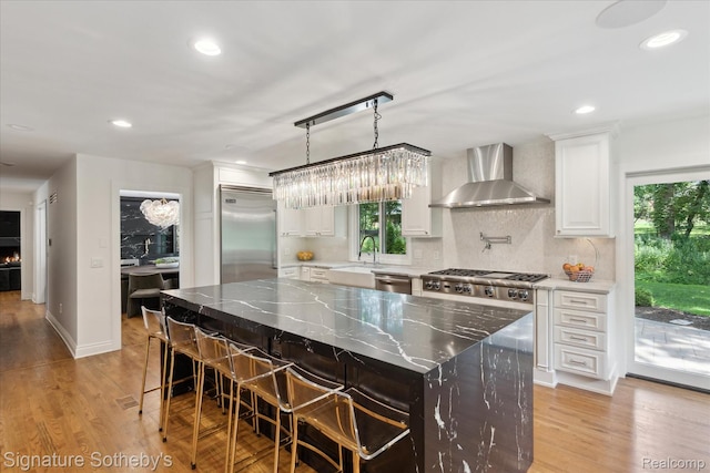 4438 Stony River Dr, Bloomfield Hills, MI 48301 - kitchen featuring appliances with stainless steel finishes, wall chimney range hood, light wood-style floors, tasteful backsplash, and recessed lighting