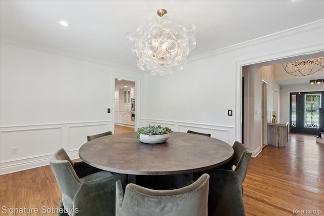 4438 Stony River Dr, Bloomfield Hills, MI 48301 - dining area with a chandelier, light wood-style flooring, ornamental molding, wainscoting, and a decorative wall