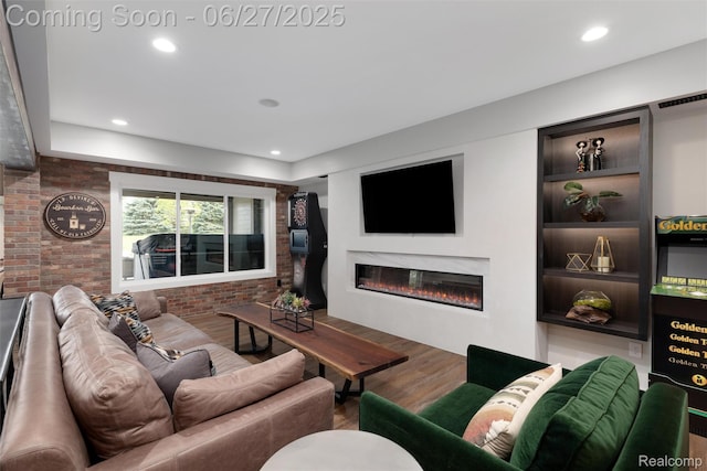 8264 Stoney Creek Dr, South Lyon, MI 48178 - living area featuring wood finished floors, a glass covered fireplace, recessed lighting, and brick wall