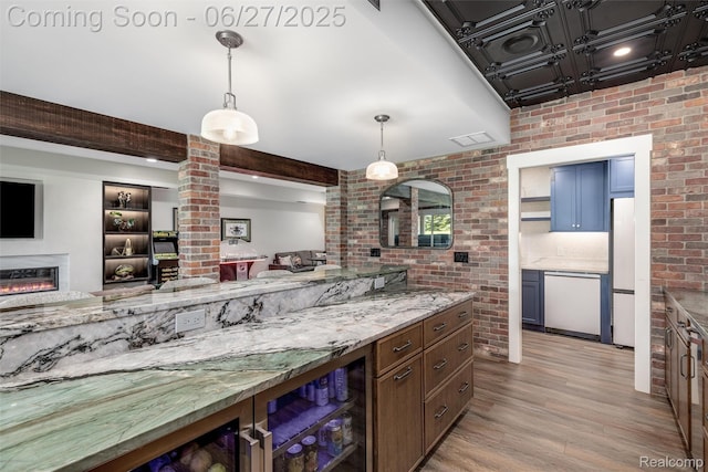8264 Stoney Creek Dr, South Lyon, MI 48178 - kitchen featuring dishwashing machine, light wood-type flooring, brick wall, a glass covered fireplace, and light stone countertops