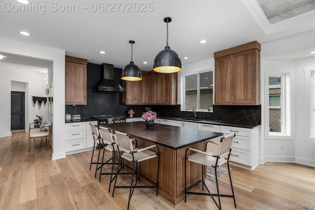 8264 Stoney Creek Dr, South Lyon, MI 48178 - kitchen featuring wall chimney exhaust hood, a kitchen breakfast bar, backsplash, recessed lighting, and light wood finished floors