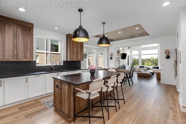 8264 Stoney Creek Dr, South Lyon, MI 48178 - kitchen featuring dark countertops, a kitchen breakfast bar, tasteful backsplash, light wood-style floors, and open floor plan