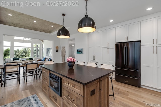 8264 Stoney Creek Dr, South Lyon, MI 48178 - kitchen featuring high end fridge, light wood-type flooring, recessed lighting, a center island, and a breakfast bar