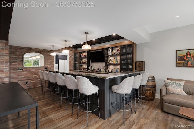 8264 Stoney Creek Dr, South Lyon, MI 48178 - indoor wet bar featuring wood finished floors, brick wall, and decorative light fixtures