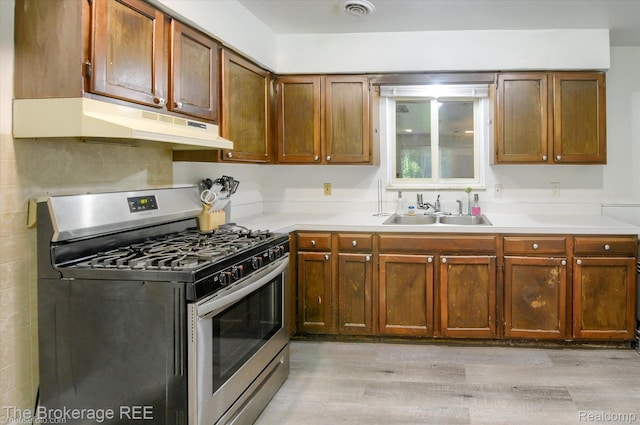 8021 Benson Rd, Mount Morris, MI 48458 - kitchen with stainless steel range with gas cooktop, under cabinet range hood, light wood-style flooring, light countertops, and brown cabinetry