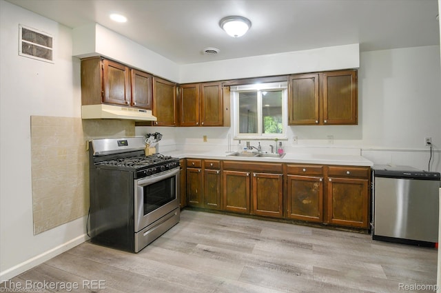 8021 Benson Rd, Mount Morris, MI 48458 - kitchen with stainless steel gas stove, under cabinet range hood, light countertops, light wood-type flooring, and refrigerator