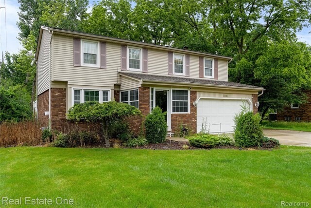 21462 Meridian Rd, Grosse Ile, MI 48138 - traditional-style home featuring concrete driveway, brick siding, an attached garage, and a front lawn
