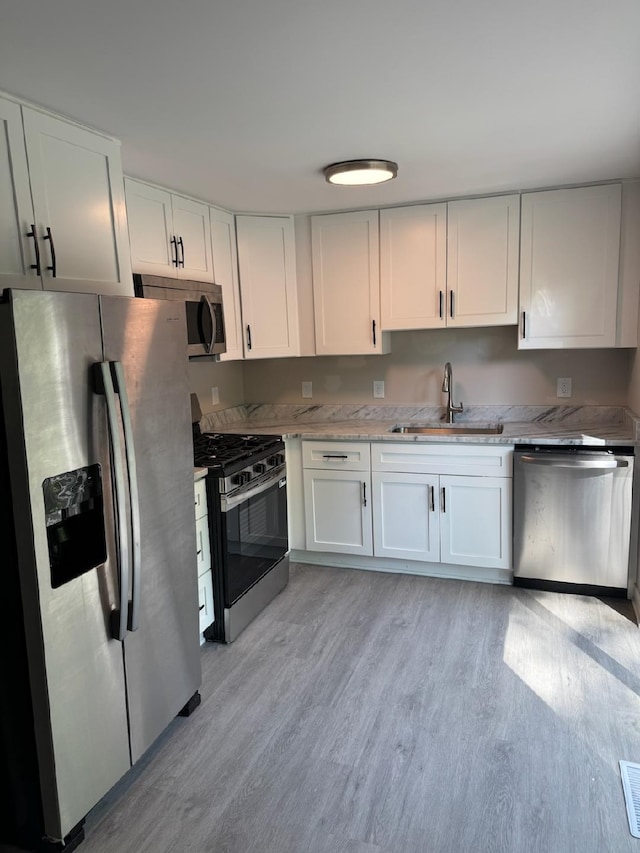 2159 E Eden Ct, Ann Arbor, MI 48108 - kitchen featuring stainless steel appliances, light wood-style floors, white cabinetry, and light stone counters