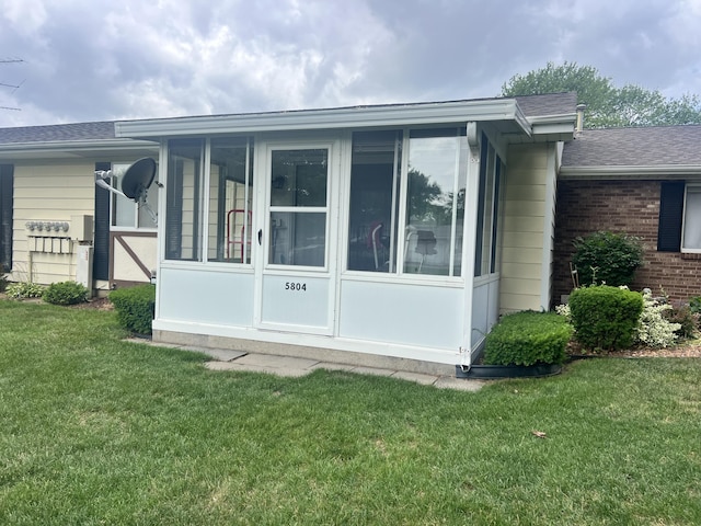 5804 Leisure S Dr SE, Grand Rapids, MI 49548 - view of side of property with a sunroom, a lawn, and a shingled roof