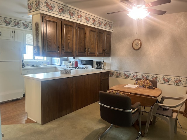 5804 Leisure S Dr SE, Grand Rapids, MI 49548 - kitchen featuring white appliances, a peninsula, a ceiling fan, light countertops, and dark brown cabinets
