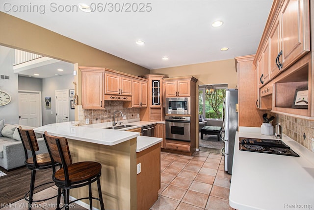 2868 Masters Ct, Pinckney, MI 48169 - kitchen with appliances with stainless steel finishes, a peninsula, decorative backsplash, a breakfast bar area, and light countertops