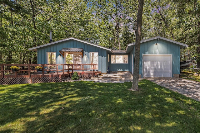 5510 W Lattin Rd, Pentwater, MI 49449 - view of front of house with a garage, a wooden deck, a front yard, and driveway