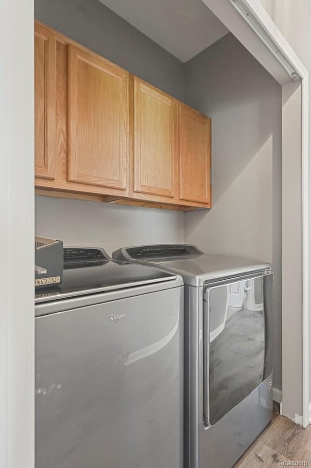 70298 Sunny Brook Ln, Macomb, MI 48062 - washroom featuring washing machine and dryer, cabinet space, and light wood-style floors