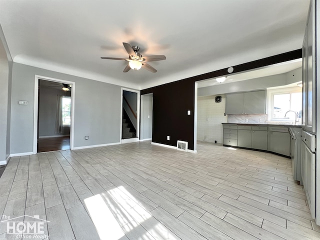 10306 Reid Rd, Swartz Creek, MI 48473 - unfurnished living room featuring a ceiling fan, light wood finished floors, and stairs