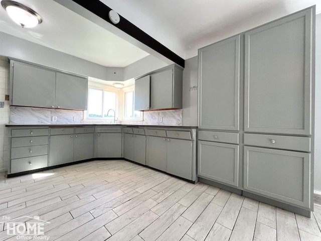 10306 Reid Rd, Swartz Creek, MI 48473 - kitchen with gray cabinets, light wood-style floors, backsplash, and dark countertops