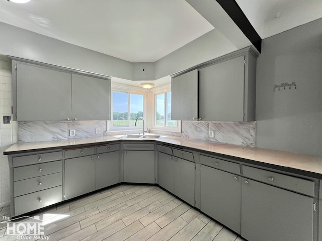 10306 Reid Rd, Swartz Creek, MI 48473 - kitchen featuring gray cabinets, backsplash, light countertops, and light wood finished floors