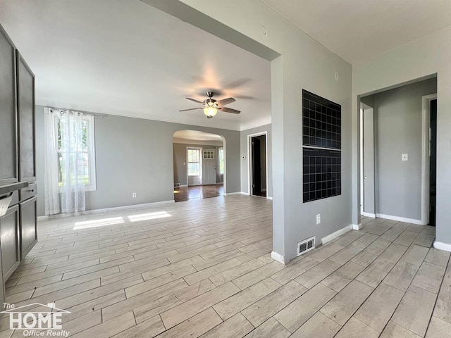 10306 Reid Rd, Swartz Creek, MI 48473 - unfurnished living room featuring arched walkways, a ceiling fan, healthy amount of natural light, and light wood finished floors