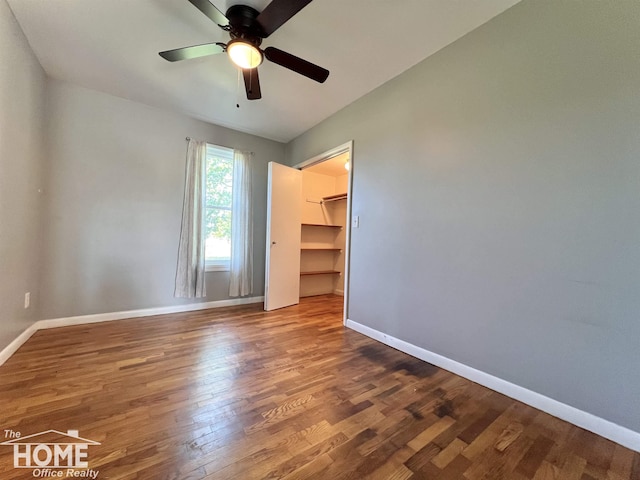 10306 Reid Rd, Swartz Creek, MI 48473 - unfurnished bedroom with wood finished floors, a walk in closet, a closet, and a ceiling fan