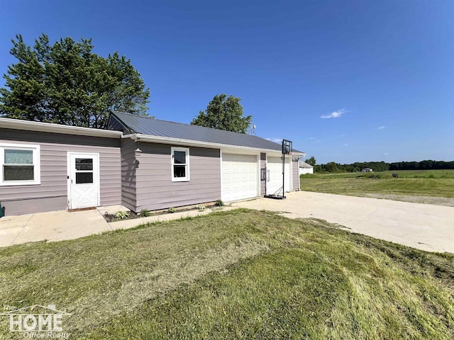 10306 Reid Rd, Swartz Creek, MI 48473 - view of side of property with concrete driveway, a garage, a lawn, and a metal roof