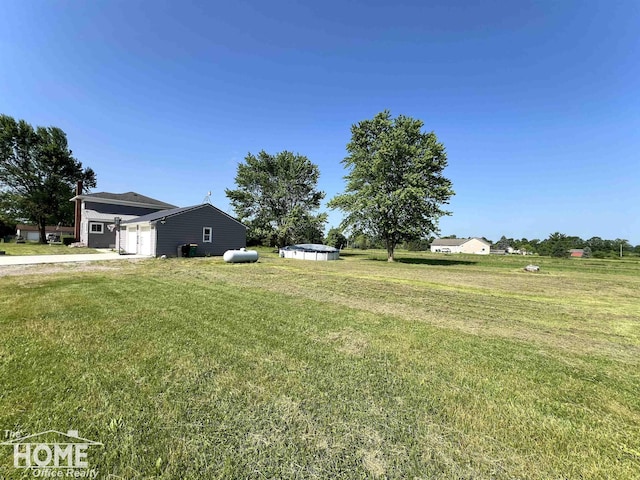 10306 Reid Rd, Swartz Creek, MI 48473 - view of grassy yard with a garage and concrete driveway