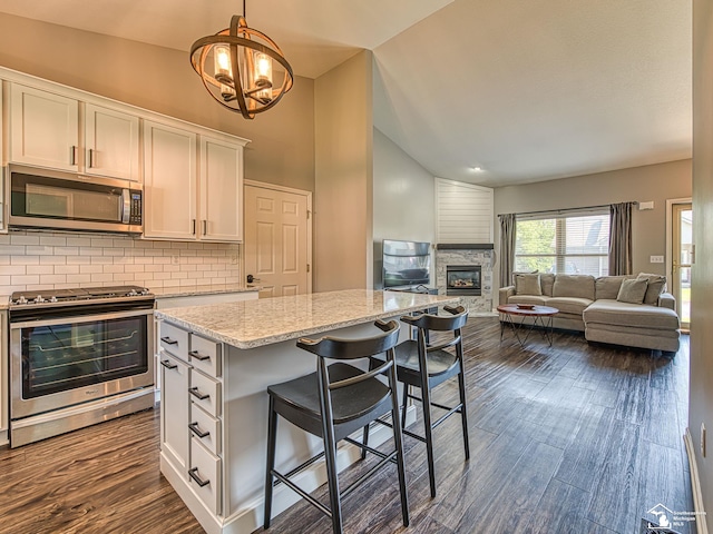 5257 Torrington Dr, Monroe, MI 48161 - kitchen featuring appliances with stainless steel finishes, lofted ceiling, white cabinets, tasteful backsplash, and a breakfast bar area