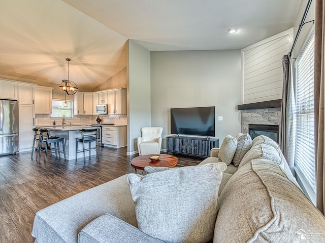 5257 Torrington Dr, Monroe, MI 48161 - living room featuring dark wood-style floors, vaulted ceiling, a fireplace, and a chandelier