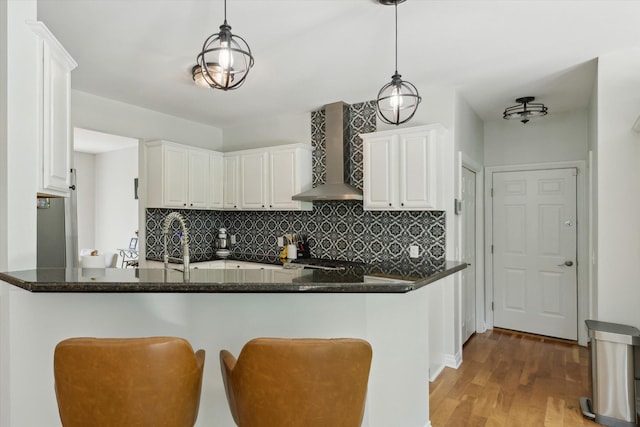 6212 Sagamore Ln, Kalamazoo, MI 49004 - kitchen with wall chimney exhaust hood, white cabinets, tasteful backsplash, and light wood-type flooring
