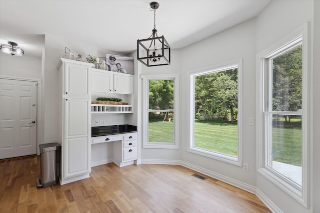 6212 Sagamore Ln, Kalamazoo, MI 49004 - unfurnished dining area with light wood-type flooring, a chandelier, built in study area, and healthy amount of natural light