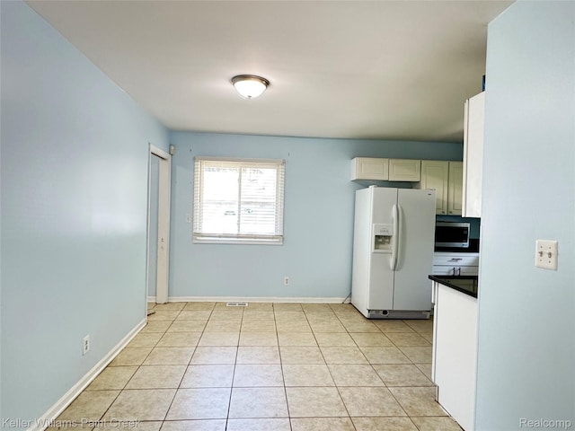 20839 Sunset Ave, Warren, MI 48091 - kitchen with white fridge with ice dispenser, stainless steel microwave, dark countertops, and light tile patterned floors