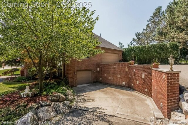 31085 Estate Woods Ct, Farmington Hills, MI 48331 - view of side of home featuring an attached garage, driveway, and brick siding