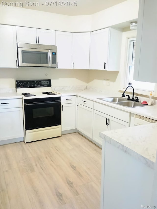 19241 Melrose Ave, Southfield, MI 48075 - kitchen with stainless steel microwave, electric range, white cabinets, light countertops, and light wood-style floors