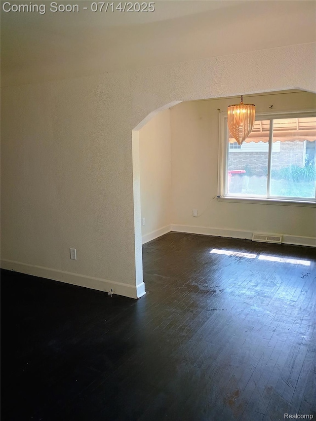 19241 Melrose Ave, Southfield, MI 48075 - unfurnished room featuring dark wood-style floors, a chandelier, and arched walkways
