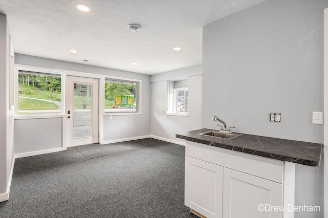 6973 W Blue Water Hwy, Saranac, MI 48881 - kitchen featuring white cabinetry, dark carpet, healthy amount of natural light, recessed lighting, and tile counters
