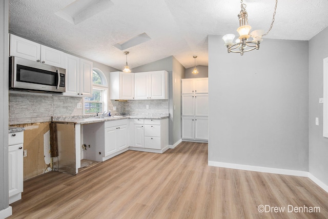 6973 W Blue Water Hwy, Saranac, MI 48881 - kitchen featuring stainless steel microwave, light wood-style floors, white cabinets, backsplash, and a textured ceiling