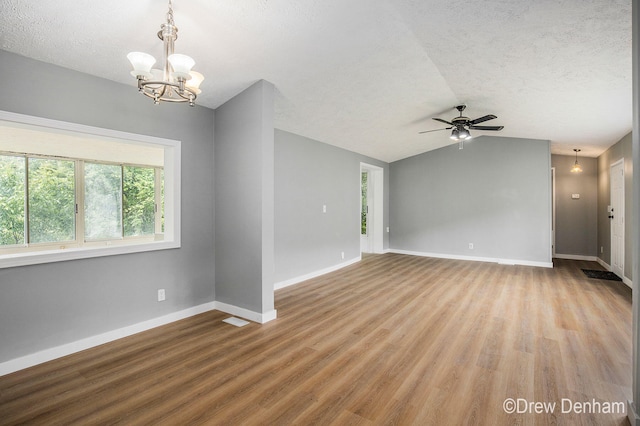 6973 W Blue Water Hwy, Saranac, MI 48881 - unfurnished living room with a textured ceiling, a chandelier, wood finished floors, vaulted ceiling, and ceiling fan