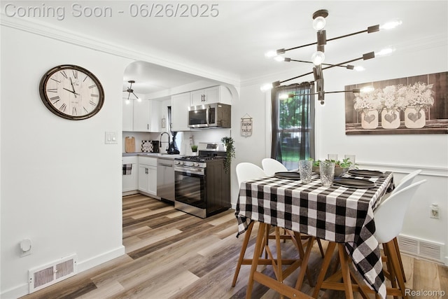 8411 Hugh St, Westland, MI 48185 - dining space with a chandelier, crown molding, and light wood-style flooring